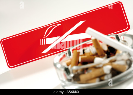 Full ashtray in front of no smoking signboard, tilt view Stock Photo