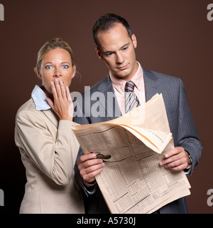 Businessman and businesswoman with newspaper, woman covering mouth Stock Photo