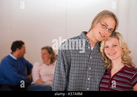 Teenage couple, parents sitting in background Stock Photo