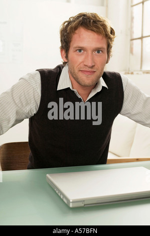 Young man sitting on desk Stock Photo