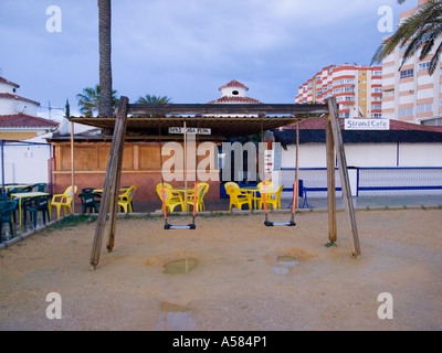 A deserted and wet children's playground in winter on the beach promenade at Torrox Costa,Costa del Sol Malaga, Andalusia, Spain Stock Photo