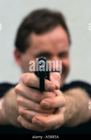 Man pointing 9mm automatic handgun directly at viewer Stock Photo