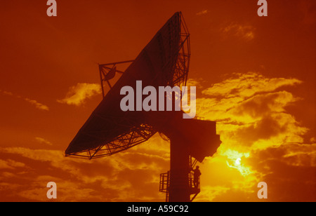 earth station satellite dish antenna sunset silhouette technician standing on tower platform Stock Photo