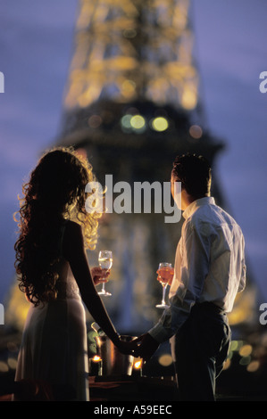 Couple with champagne glasses on River Seine houseboat under Eiffel Tower at night Stock Photo