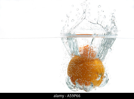 orange dropped into clear water Stock Photo