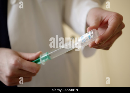WOMAN DOCTOR PREPARES A SYRINGE FOR AN INJECTION Stock Photo