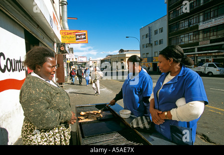 A woman buying grilled meat from a roadside stall Stock Photo