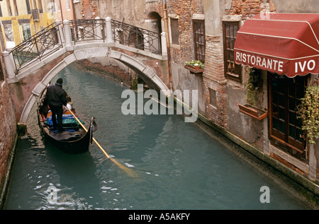 A gondola passes a restaurant on a canal in Venice Italy Stock Photo