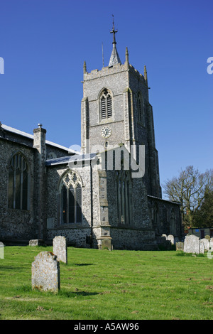 A typical British church tower stands in a lush green cemetary with iconic ancient tombstones Norfolk England UK GB Britain Stock Photo