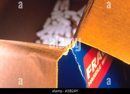 Open empty, used cardboard box. Packing peanuts, styrofoam pellets, at the bottom. Mailing or storage carton torn with fragile sticker label. Close up Stock Photo