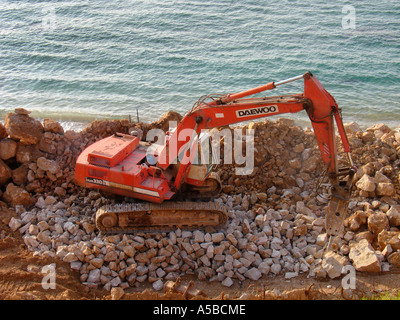 Backhoe excavator engaging in promenade construction work at the Mediterranean seashore of Tel Aviv in Israel Stock Photo