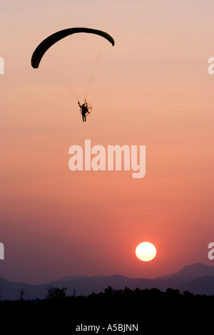Silhouette profile of man using a paramotor in south India in the evening time against a setting sun background Stock Photo