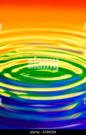 Rainbow water ripples. Water on a plate mirror with reflected colour background. Stock Photo