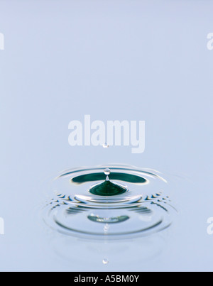 Water drop reflected onto blue coloured mirrored background. Water on a plate mirror with reflected colour Stock Photo