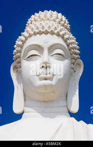 White Buddha statue against blue sky portrait in South India Stock Photo