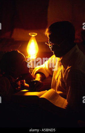 In a small one room house in Mississippi a african American grandfather reads verses out of the Bible Stock Photo