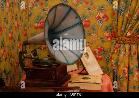 Old portable wind-up gramophone loudspeaker in a living room decorated with floral wallpaper