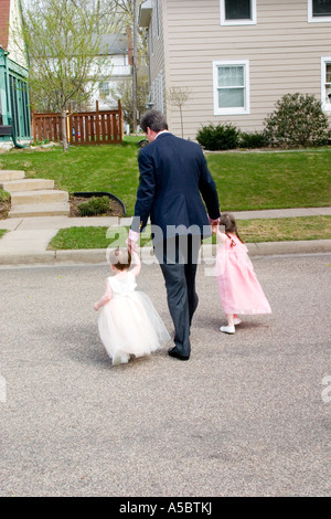Dad walking daughters in their Easter duds across street. St Paul Minnesota USA Stock Photo