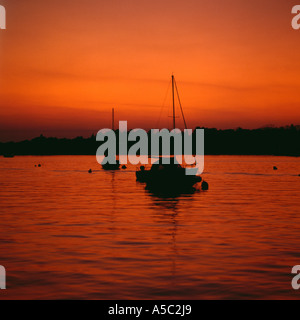 Moored yachts silhouetted against afterglow from sunset, Oulton Broad, Suffolk, UK. Stock Photo