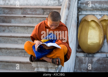 Novice Monk Reading a Book Sitting on the Stupa Phu That Udumxai or Muang Xai Laos Stock Photo