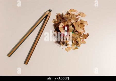 Red pencil sharpener with two coloured pencils and shavings on white table background Stock Photo