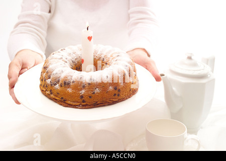 Woman holding out birthday cake with one candle Stock Photo