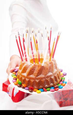 Woman holding out birthday cake with candles Stock Photo