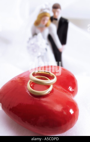 Bride and groom figurines with wedding rings on heart Stock Photo