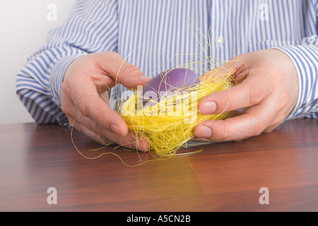 Middle aged man holding bird's nest with Easter egg in his hands Stock Photo
