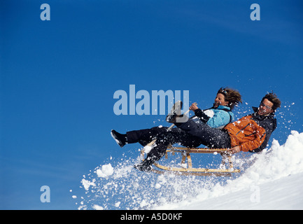 Young couple on sledge jumping, side view Stock Photo
