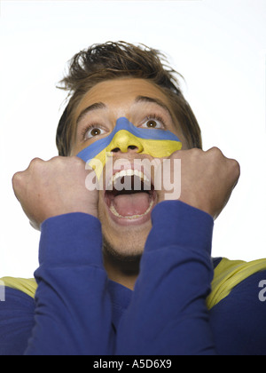 Young man with Ukrainian flag painted on face, mouth open, looking up, close-up Stock Photo