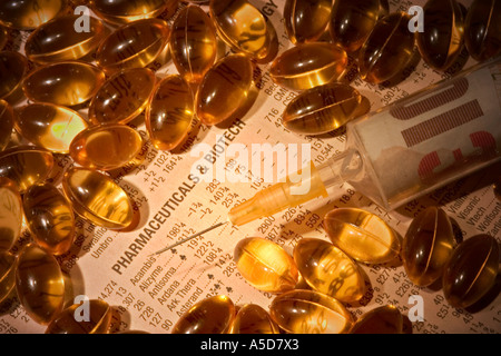 Close up of hypodermic needle and syringe filled with money on a financial newspaper surrounded by pills Stock Photo