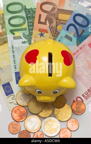 Piggy bank on various euro banknotes and coins Stock Photo