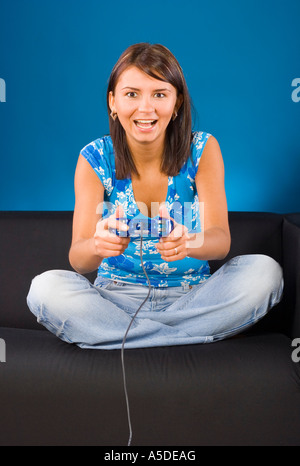 Young woman sitting on the black sofa with a computer pad in her hand Blue background in studio Stock Photo