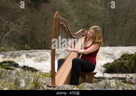 Woman playing a Telynau Teifi welsh harp outdoors outside at Cenarth Falls on the River Teifi Ceredigion wales UK Stock Photo