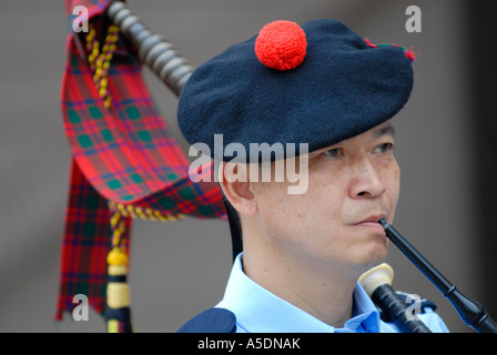 Chinese policeman wearing the traditional Scottish Balmoral hat blowing bagpipe flute during Chinese Lunar New Year celebrations in Hong Kong China Stock Photo