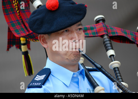 Chinese policeman wearing the traditional Scottish Balmoral hat blowing bagpipe flute during Chinese Lunar New Year celebrations in Hong Kong China Stock Photo