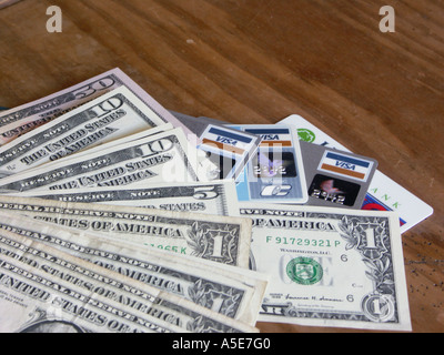 American dollar bills or notes of various denominations alongside credit or debit cards on a table. Stock Photo