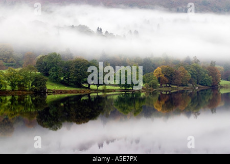 Reflections in a still Grassmere lake on a misty morning Stock Photo