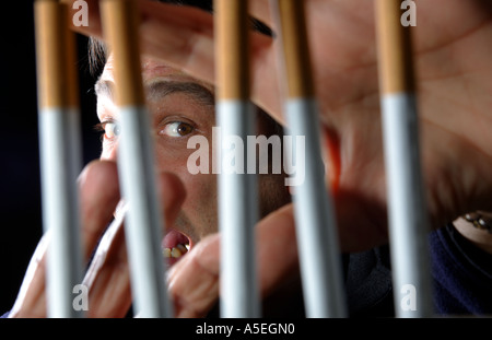 Smoker trapped behind the prison bars of addiction to nicotine Stock Photo