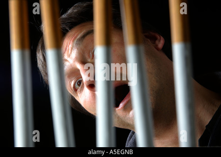 Smoker trapped behind the prison bars of addiction to nicotine Stock Photo