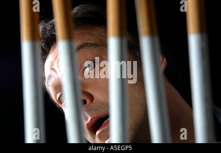 Smoker trapped behind the prison bars of addiction to nicotine Stock Photo