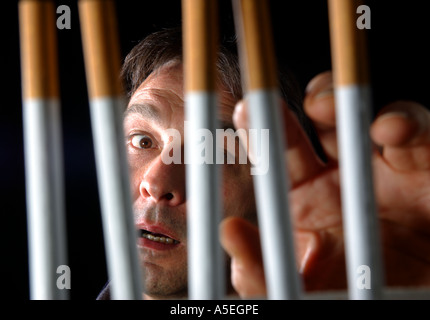 Smoker trapped behind the prison bars of addiction to nicotine Stock Photo