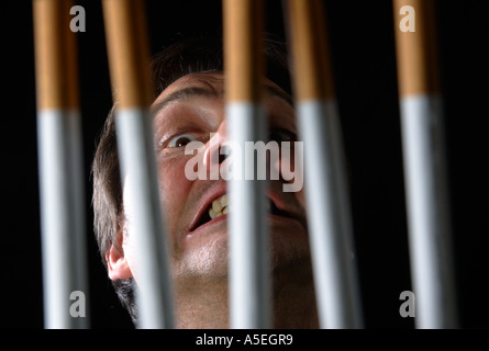 Smoker trapped behind the prison bars of addiction to nicotine Stock Photo