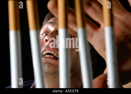 Smoker trapped behind the prison bars of addiction to nicotine Stock Photo