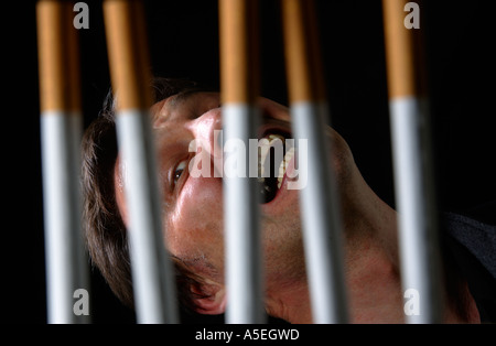 Smoker trapped behind the prison bars of addiction to nicotine Stock Photo