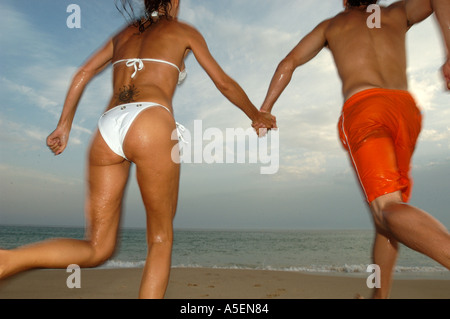 holding hands running into the sea man and woman being playful man and woman being free man and woman having fun Stock Photo