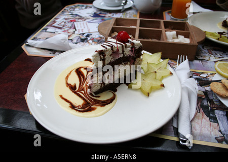 Gourmet slice of black forest cake garnished with starfruit and vanilla cream swirl. Stock Photo