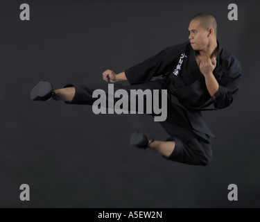 Black belt karate instructor doing a flying sidekick black background Stock Photo