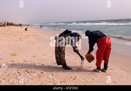 Couple in traditional clothing collecting sand on Nouakchott beach, Mauritania, Africa Stock Photo